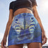 A high-waisted, bodycon mini skirt with a tight, fitted silhouette ending mid-thigh. The skirt features a vibrant, all-over graphic print of a mirrored zebra head in electric and royal blue tones against a dark blue, pixelated background. The zebra's stripes have a textured, glittery appearance in shades of silver and light blue. The skirt is made from a smooth, stretchy performance knit fabric with a subtle sheen, designed to hug the body's curves.
